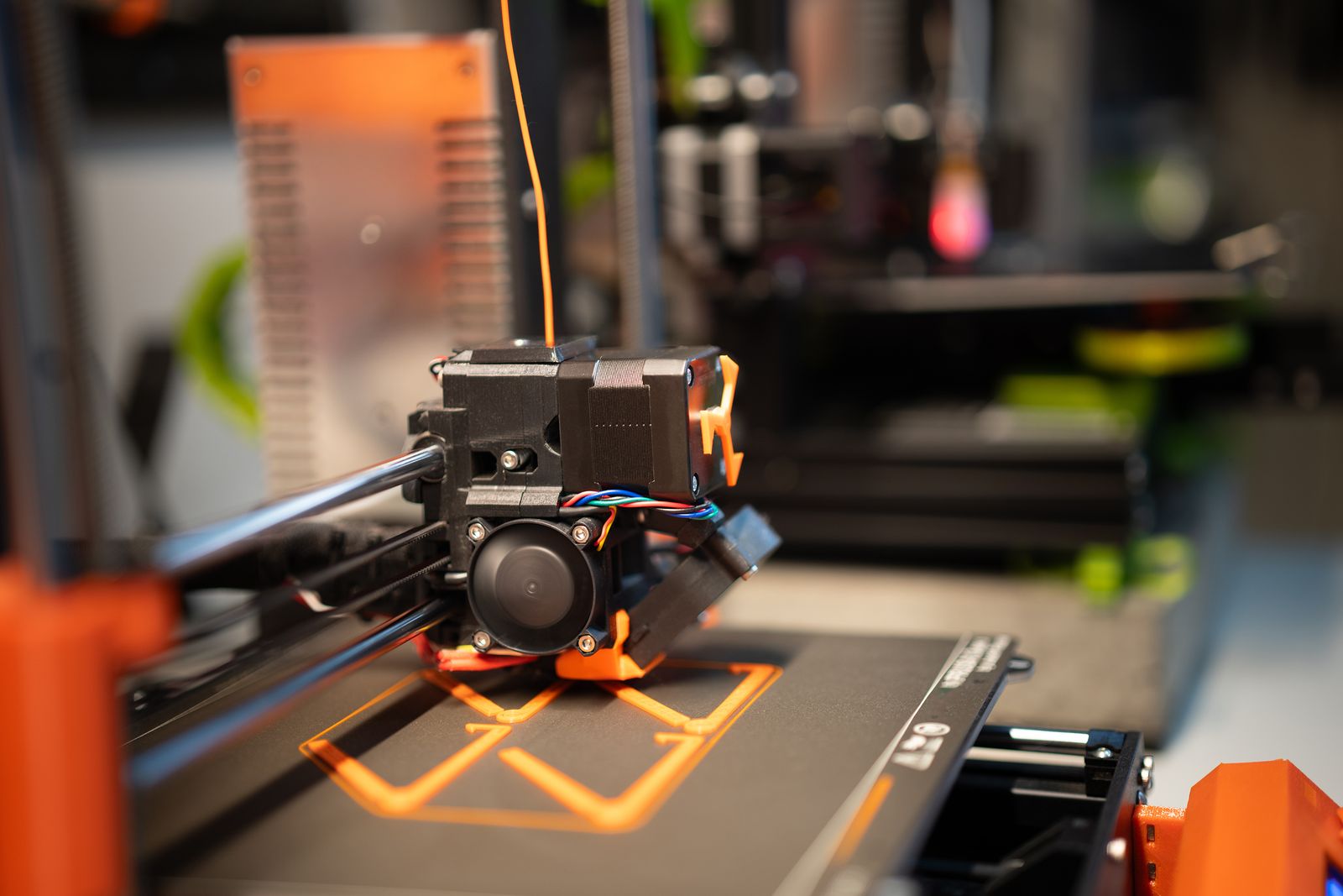 FDM 3D printer making an orange prototype in an office