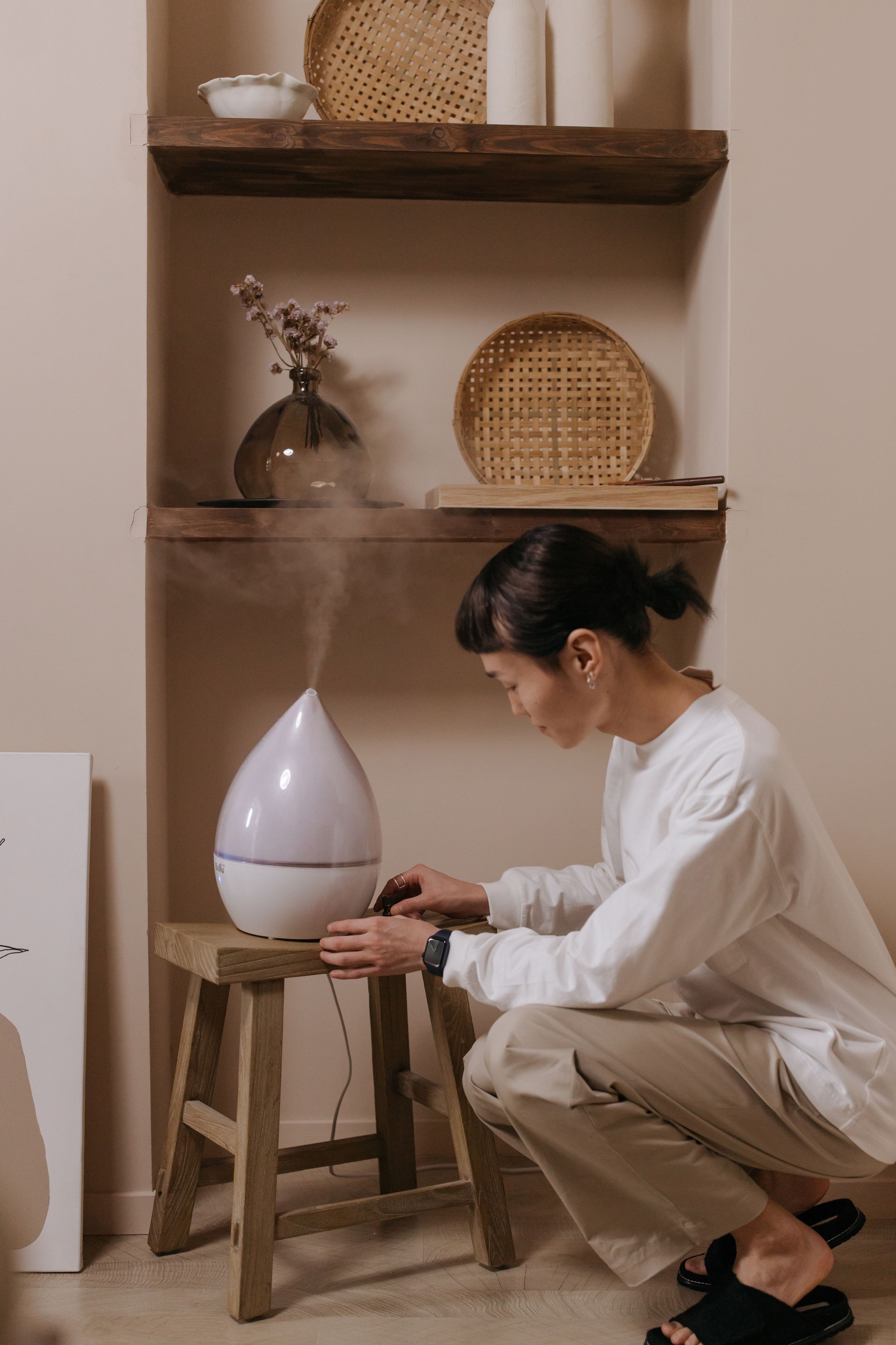 Woman adjusting a humidifier in a softly lit room