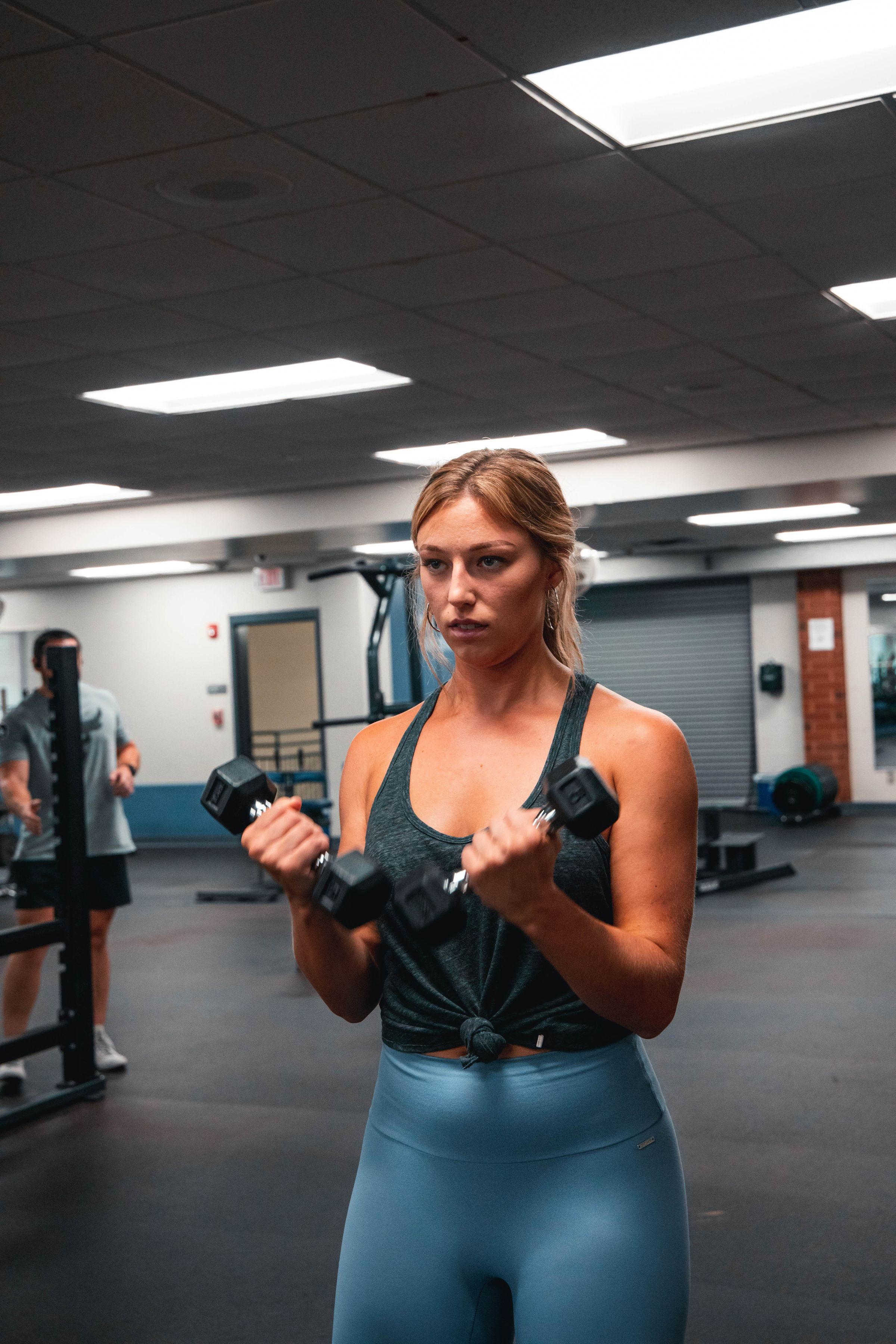 Woman performing standing biceps curls with two dumbbells