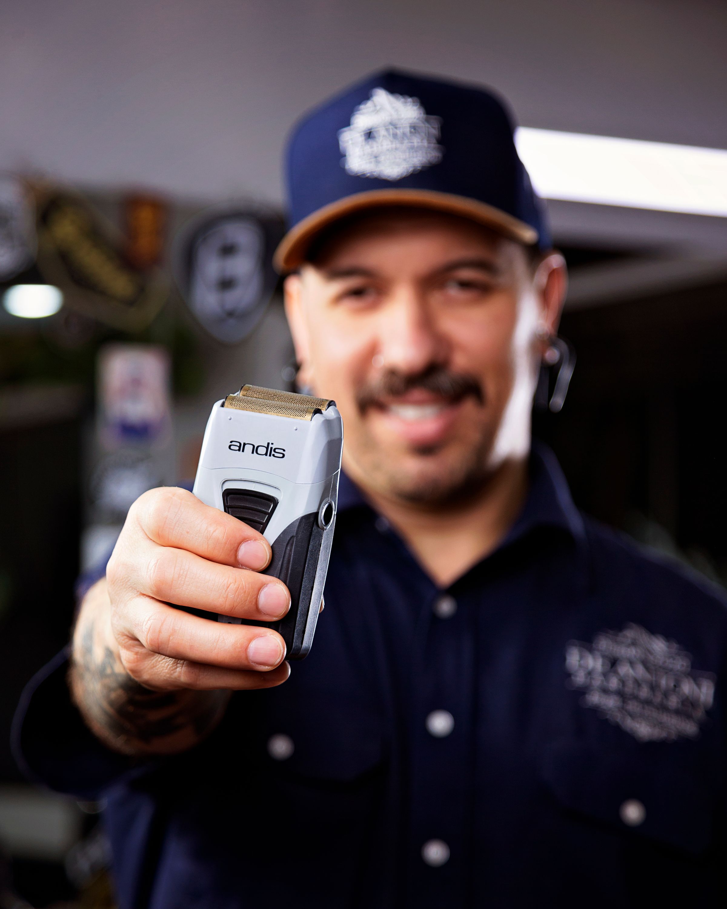 Barber displaying a cordless electric shaver in a barbershop
