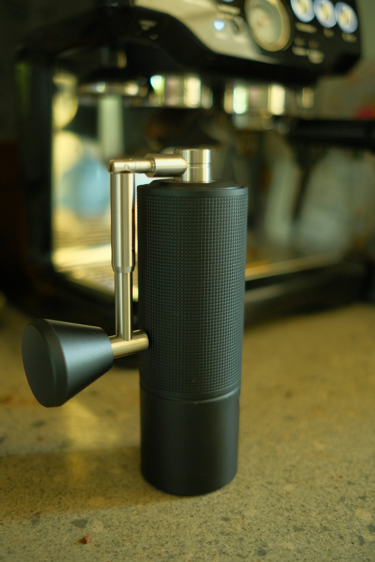 Manual coffee grinder in front of an espresso machine