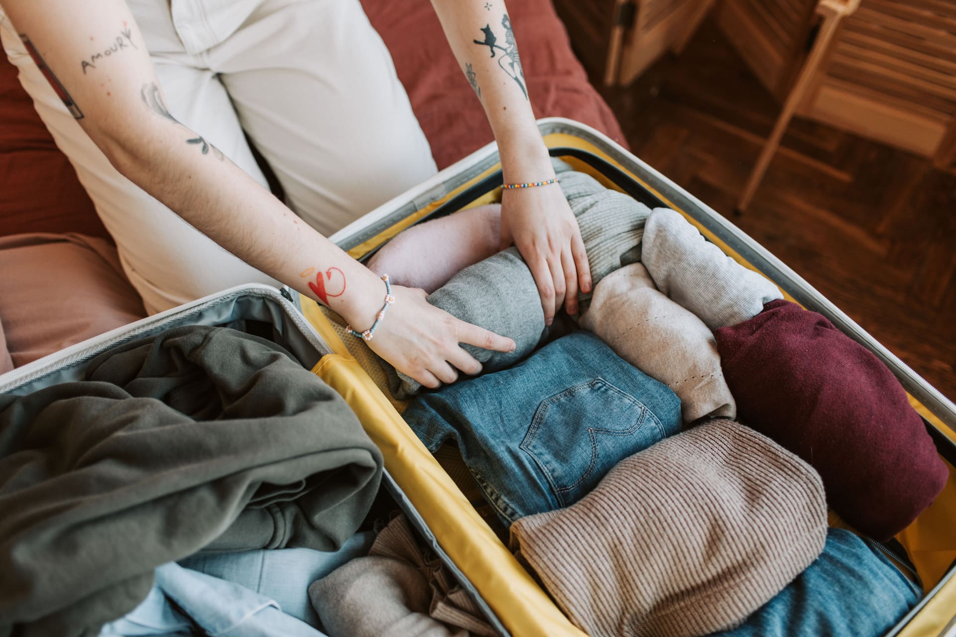 Traveler arranging rolled clothes inside an open carry-on suitcase