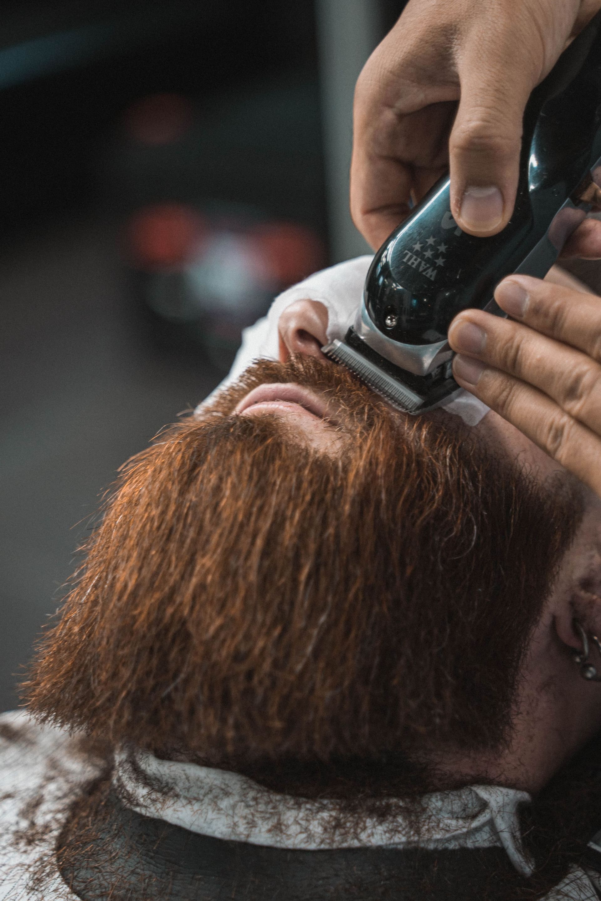 Barber guiding an electric shaver carefully along a man's beard