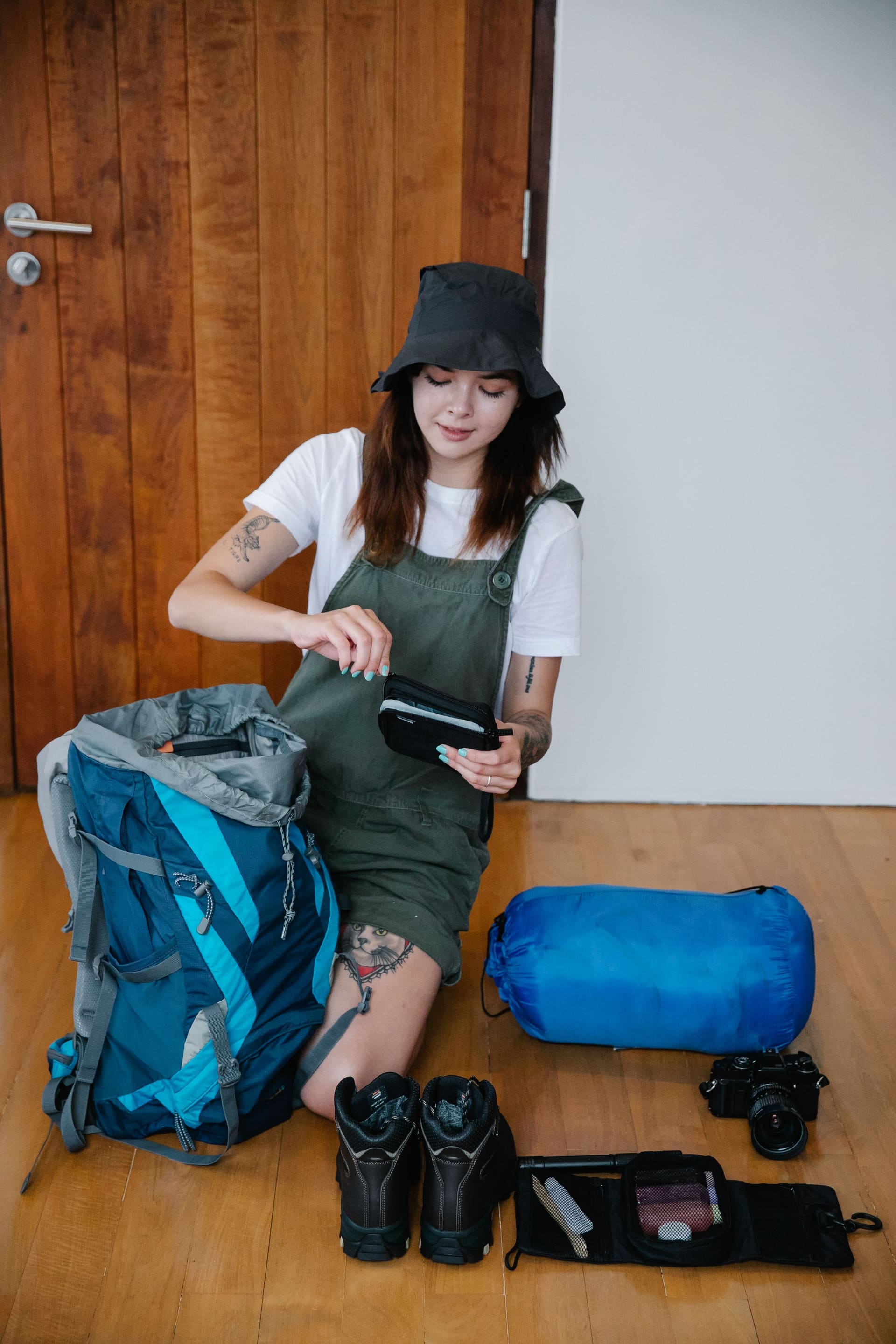 Traveler organizing equipment beside an open hiking backpack