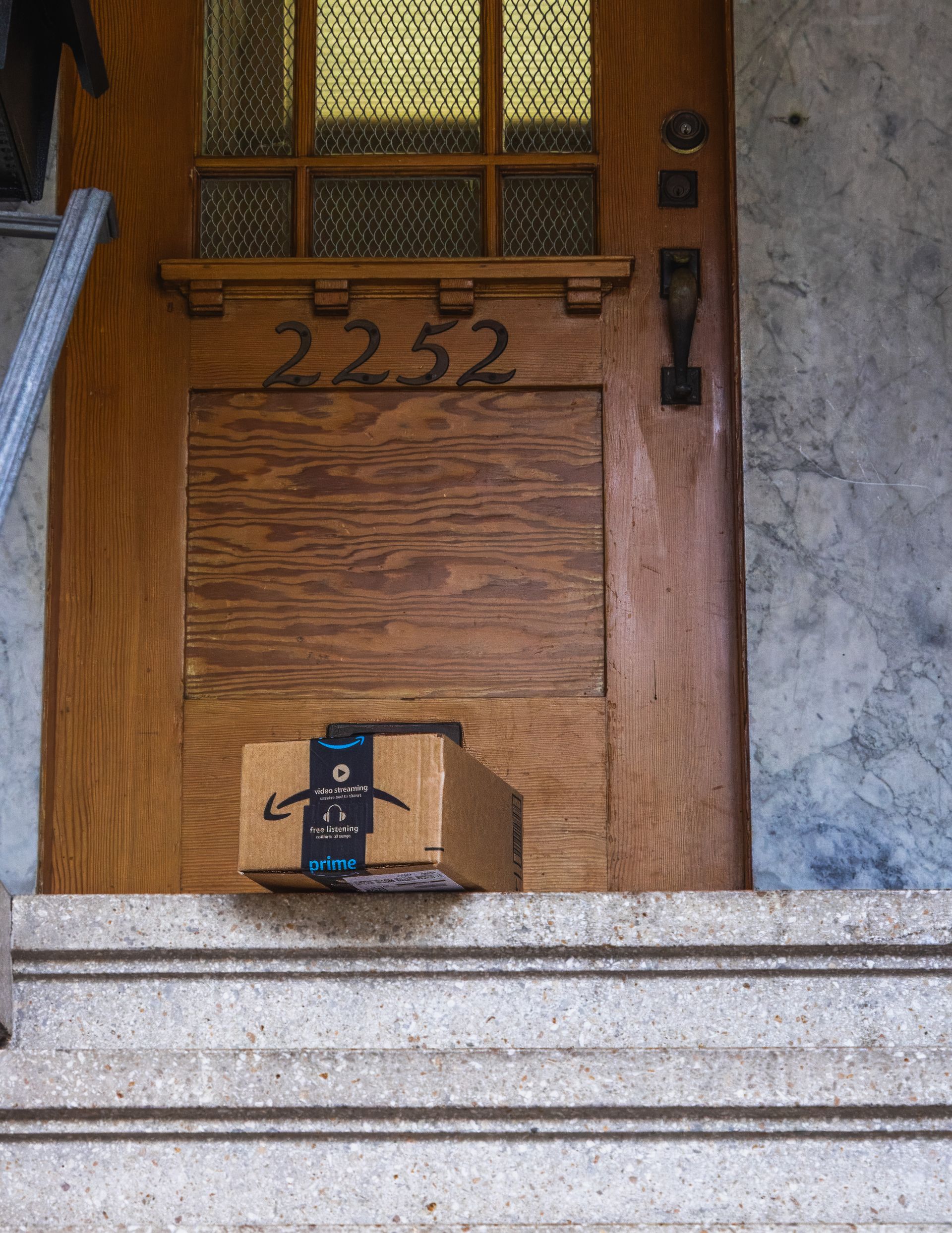 Amazon delivery box on the doorstep of a wooden front door