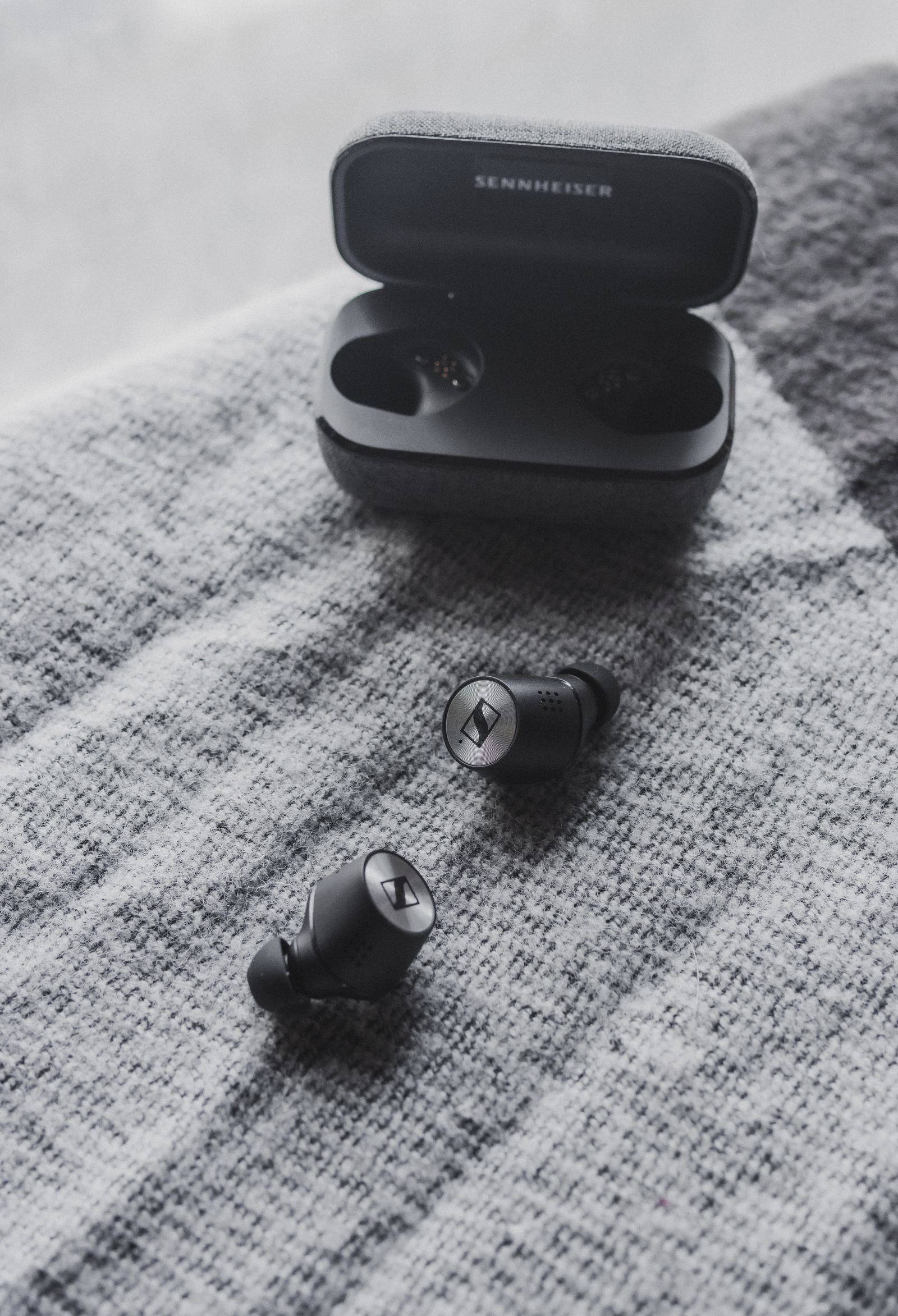 Pair of black wireless earbuds beside their charging case