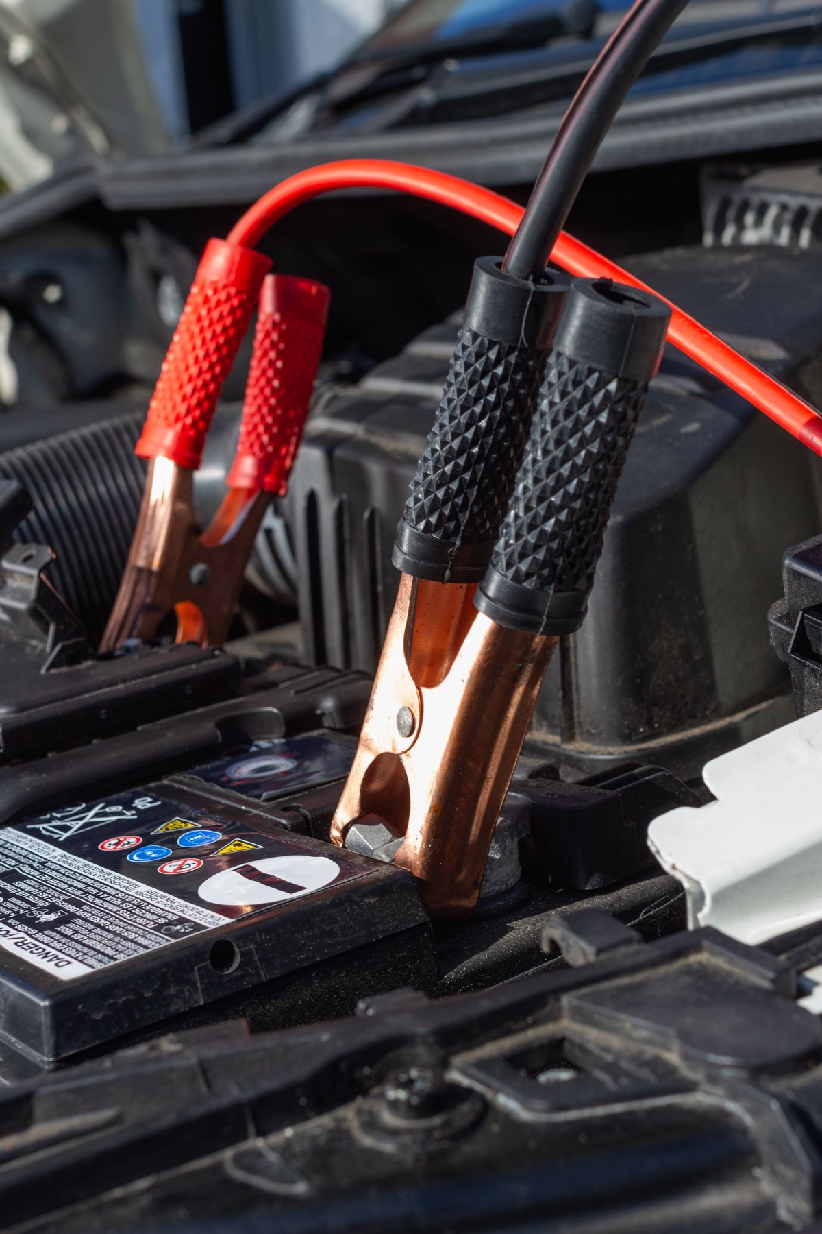 Red and black charging clamps connected to a car battery