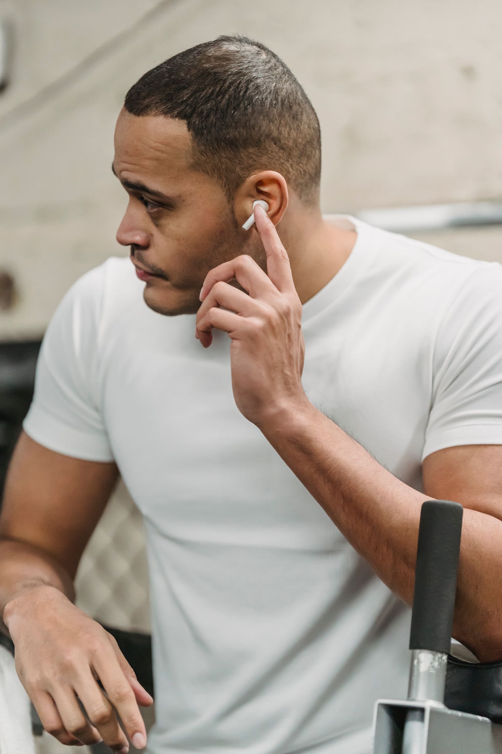 Athlete wearing true wireless earbuds while resting in a gym